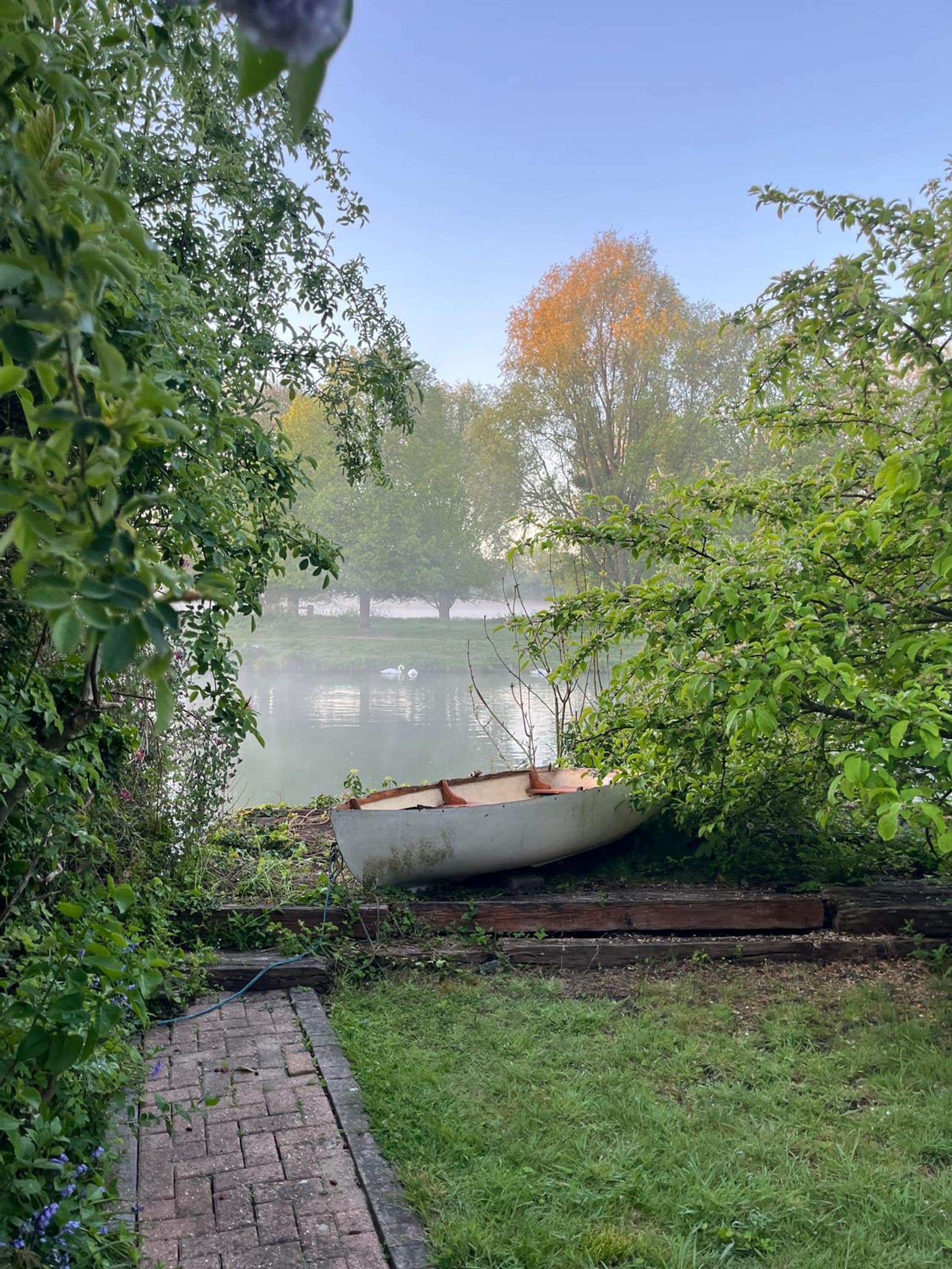 A boat docked near a calm lake surrounded by lush greenery.