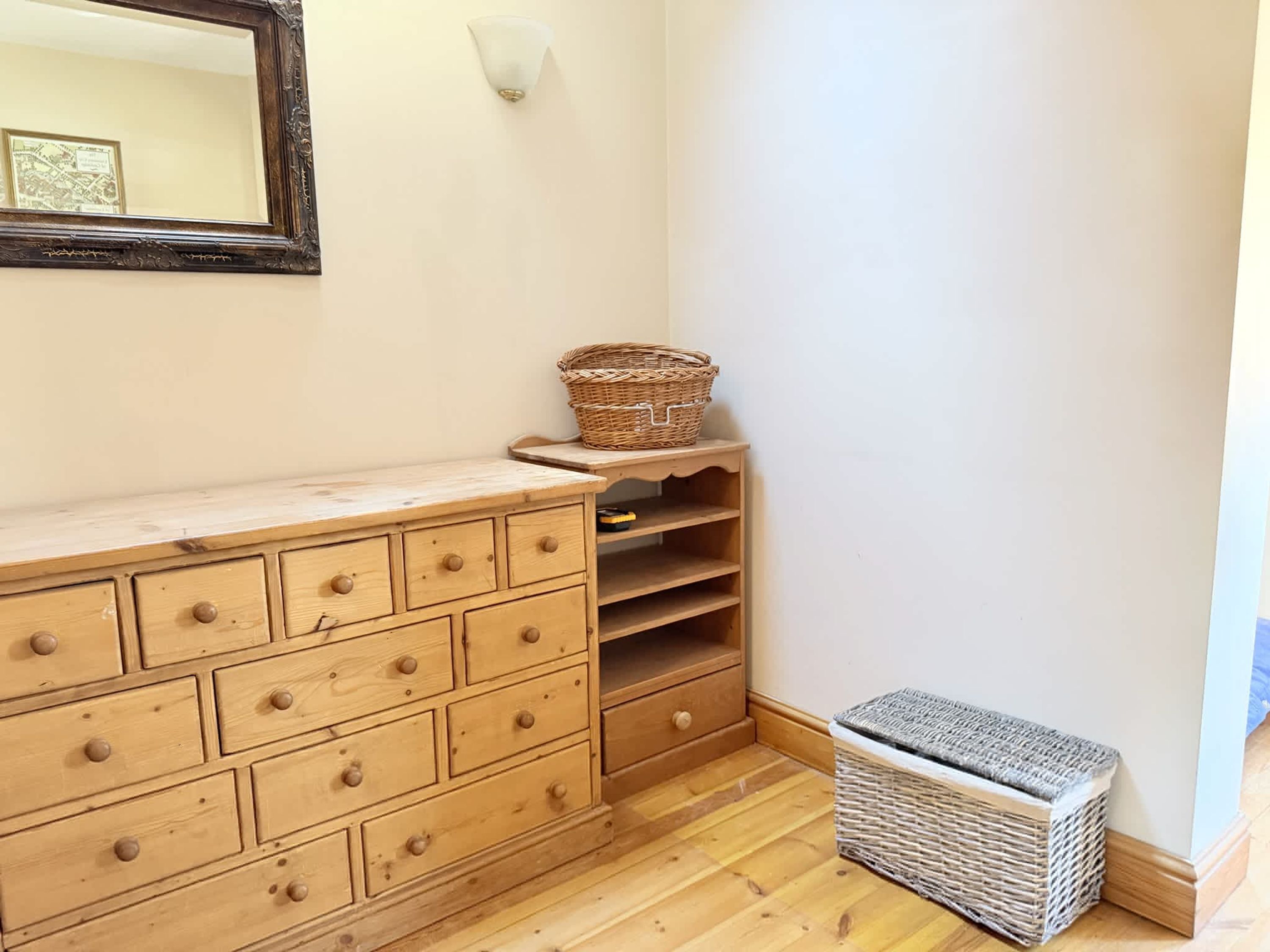 Un aparador de madera con cajones, una cesta de mimbre y otra cesta de mimbre en un estante.