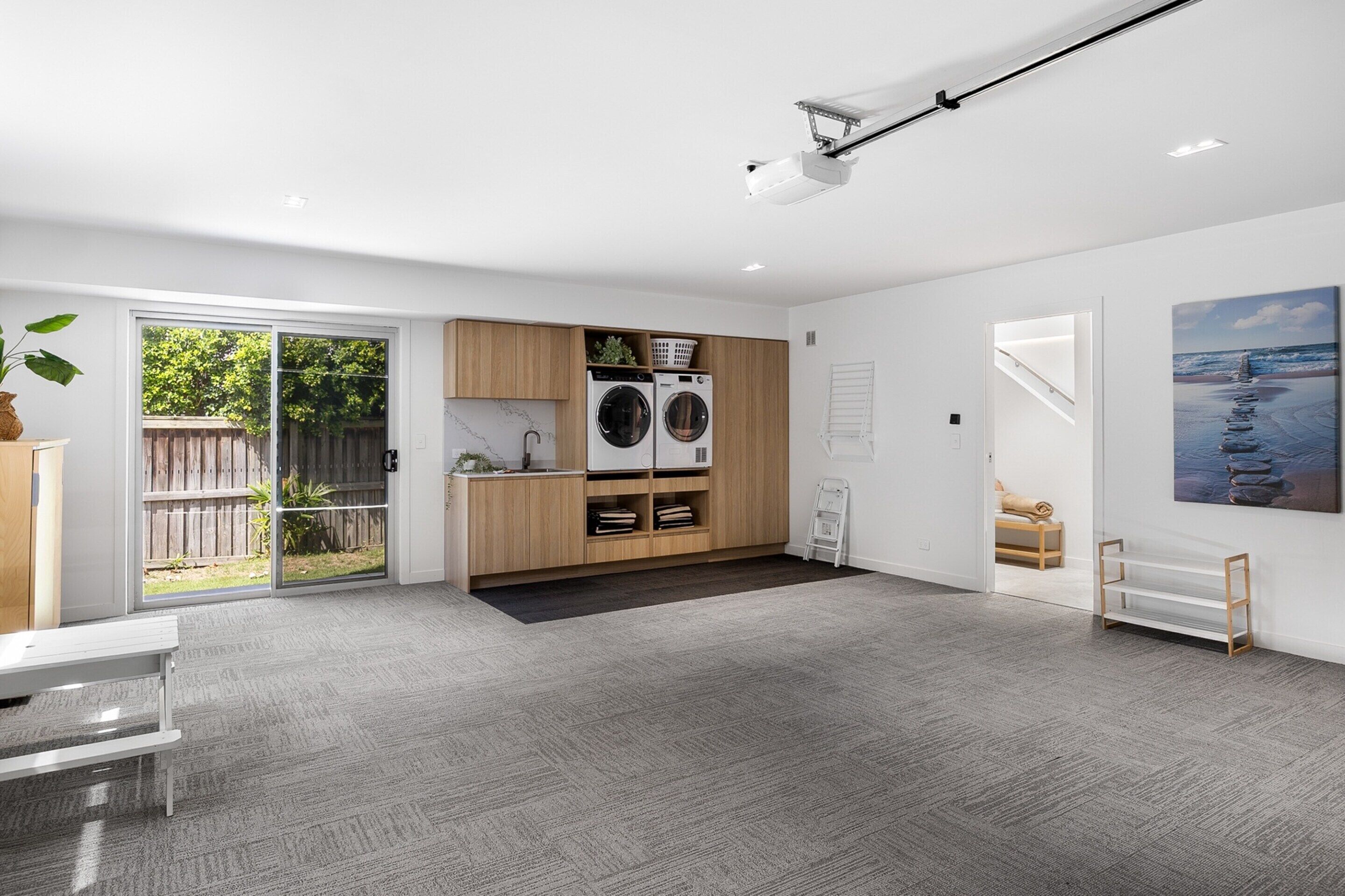 A modern kitchen with built-in appliances, a sliding glass door to a backyard, and a minimalist design.