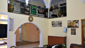 Un hall d’entrée avec un comptoir de réception, une horloge, un canapé et un escalier.