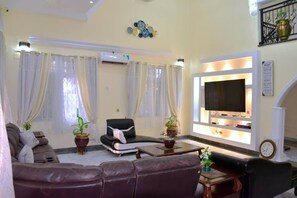 Un salon avec un canapé, une table basse, un téléviseur et une plante en pot.