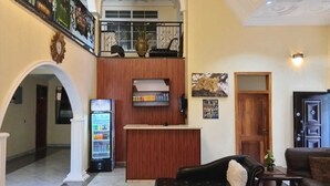 Un hall d’entrée avec un comptoir de réception, un réfrigérateur, un canapé et une porte.
