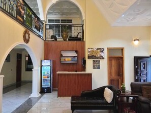 Un hall d’entrée avec un comptoir de réception, un réfrigérateur, un canapé et une porte.