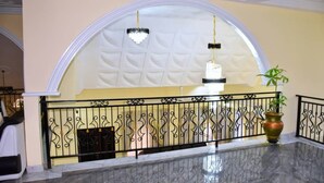 Un hall d’entrée doté d’un sol en marbre, d’un plafond voûté blanc et de rampes décoratives en métal.