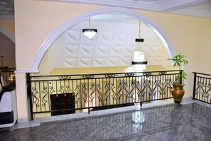 Un hall d’entrée doté d’un sol en marbre, d’un plafond voûté blanc et de rampes décoratives en métal.