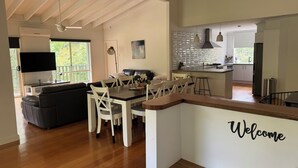Una cocina moderna con comedor, televisor montado en la pared y un cartel de 'Welcome'.