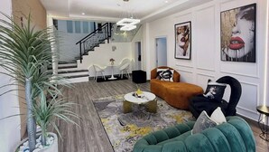 A modern living room with a staircase, a green sofa, and a coffee table. - EIO SHORTLET (Abuja)