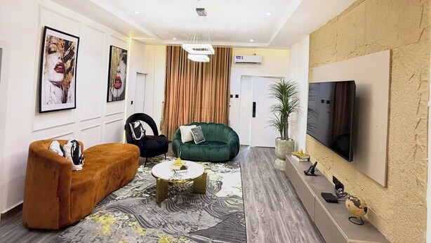A modern living room with a sofa, armchair, and a coffee table. - EIO SHORTLET (Abuja)