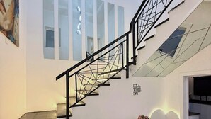 A modern interior with a staircase, a dining area, and a painting on the wall. - EIO SHORTLET (Abuja)