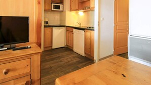 A compact kitchen with wooden cabinets, a microwave, a coffee maker, and a dishwasher. - Family Apartment in La Foux D'allos (Allos)
