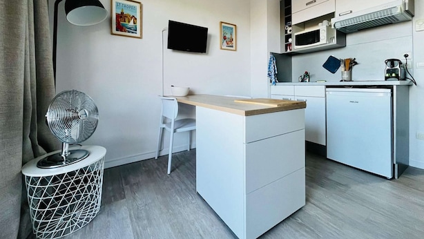 Une cuisine compacte équipée d’un four à micro-ondes, d’un petit réfrigérateur, d’une table à manger et d’une chaise.