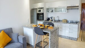 Una cocina compacta con una isla central, horno empotrado y refrigerador.