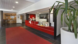 A reception area with a red counter, a large potted plant, and a wall with a sign reading 'Business Center.' - La Foux D'allos - Les Chalets du Verdon (Allos)