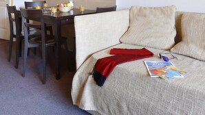 A room with a dining table, chairs, a sofa, and two framed pictures on the wall. - La Foux D'allos - Les Chalets du Verdon (Allos)