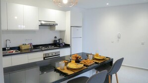 Een moderne keuken met een centraal eiland, roestvrijstalen apparatuur en een geometrische hanglamp.