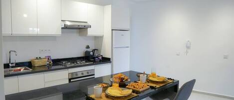Een moderne keuken met een centraal eiland, roestvrijstalen apparatuur en een geometrische hanglamp.