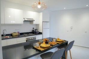 A modern kitchen with a central island, stainless steel appliances, and a geometric pendant light. - Vue Majorelle: 2 suites- Private terrace-parking area (Marrakesh)