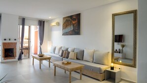 Een woonkamer met een bank, een salontafel, een open haard en een grote spiegel.