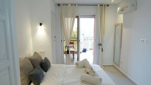 Een slaapkamer met een bed, kussens, een spiegel en uitzicht op het omliggende landschap.