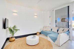 Ein modernes Wohnzimmer mit einer Couch, einem Couchtisch, einem Fernseher und einer Pflanze.