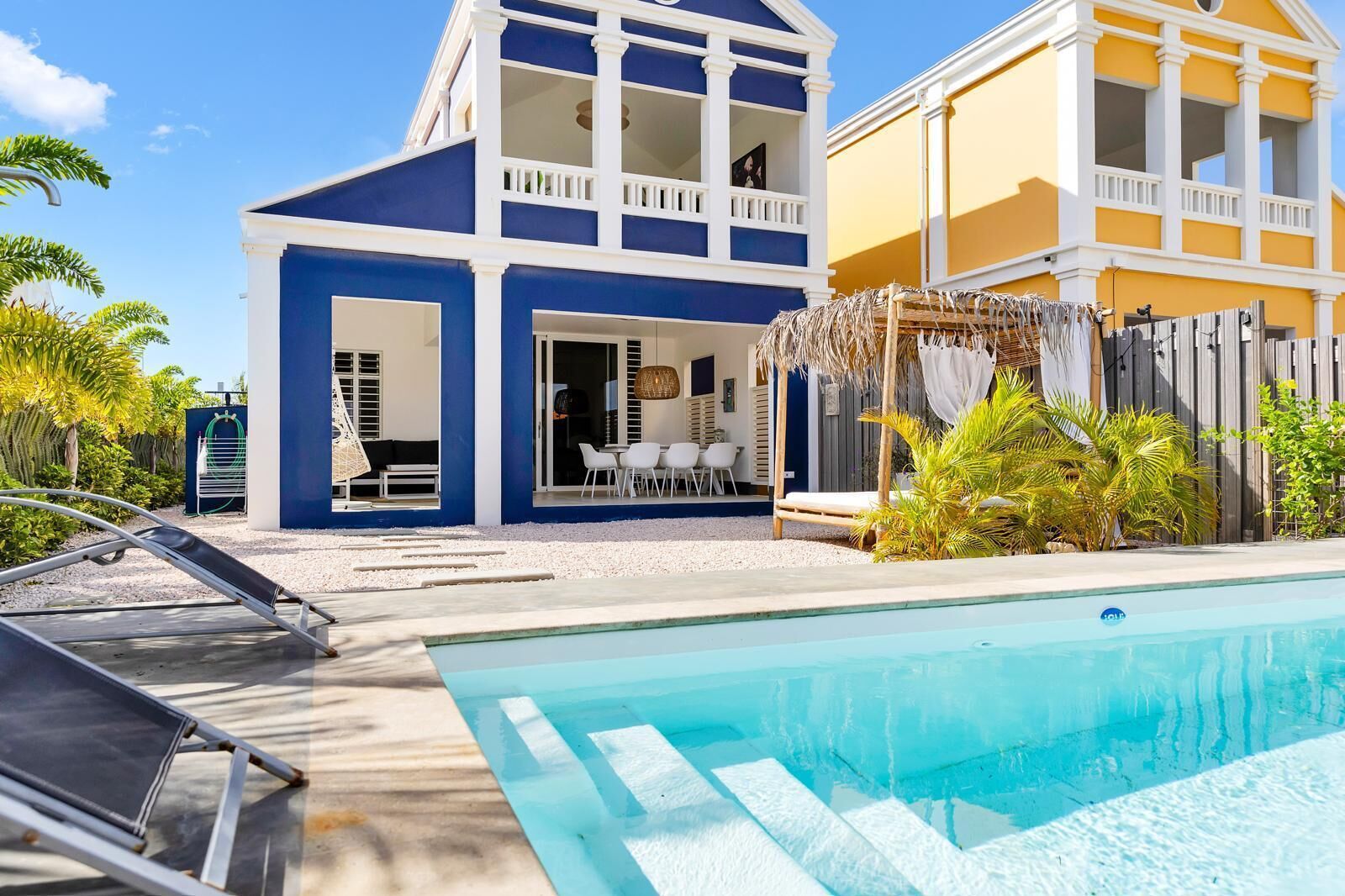 Ein zweistöckiges Haus mit Pool, Außenbereich zum Sitzen und einem umzäunten Garten.