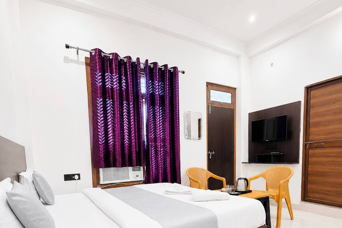 Ein Hotelzimmer mit einem Bett, einem Schreibtisch mit Telefon, einem Fernseher, einem Sessel und einem Kleiderschrank.
