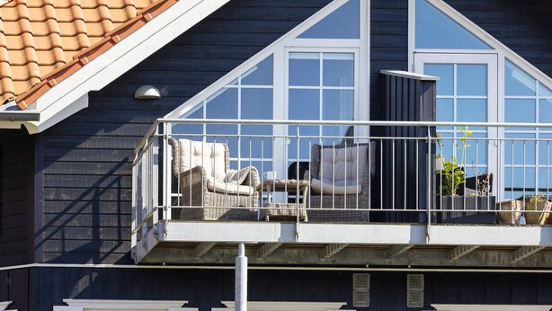Un balcon agrémenté de meubles en osier et de plantes en pot.