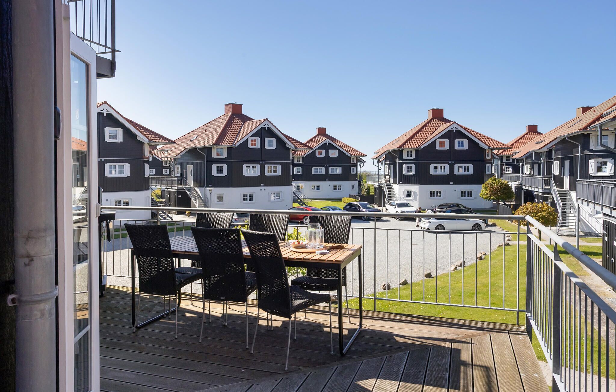 Ein Balkon mit Sitzgelegenheit, Blick auf Wohnhäuser und einem klaren Himmel.