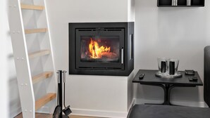 Une pièce avec une cheminée, une table avec des verres et une échelle appuyée contre le mur.