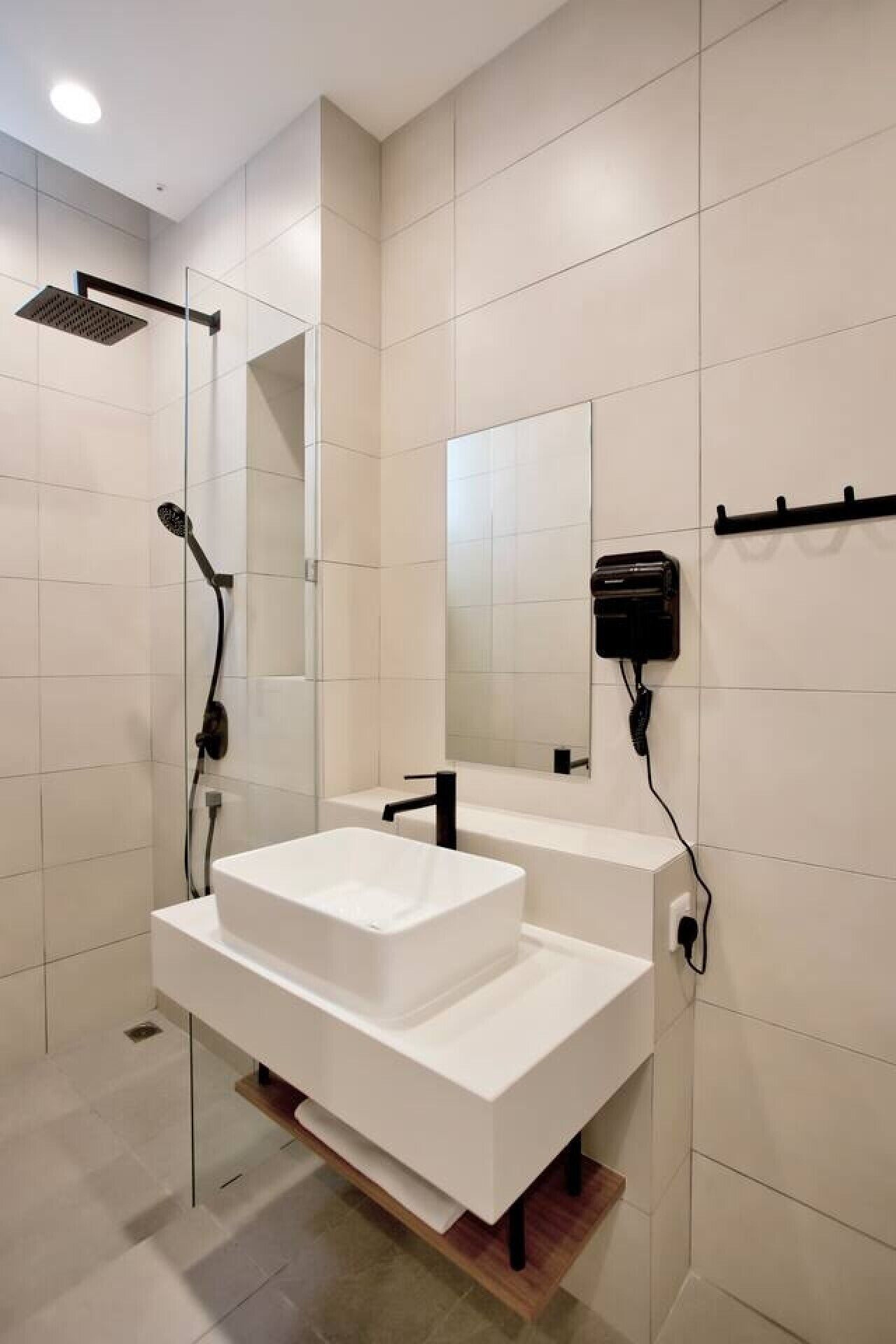 A modern bathroom with a glass-enclosed shower, a white sink, and a mirror.