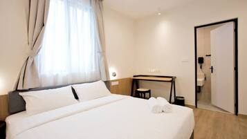 Een hotelkamer met een bed, bureau, stoel, spiegel en een deur.