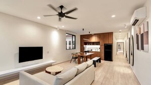 Una sala de estar moderna con sofá, televisor y comedor.