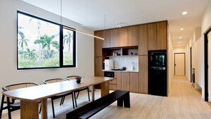 Una cocina moderna con armarios de madera, una mesa de comedor con sillas y un ventanal con vistas a palmeras.