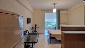 Une cuisine compacte comprenant un réfrigérateur, une table à manger avec des chaises, une petite table d’appoint et une fenêtre donnant sur un beau paysage.