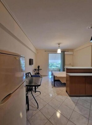 A compact kitchen with a refrigerator, a dining table with chairs, a small side table, and a window with a view. - Cozy and Urban City Center Heaven (Athina)