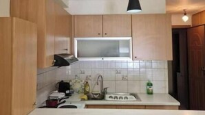 Une cuisine avec des meubles de rangement en bois, un plan de travail blanc, un évier et un luminaire suspendu.