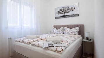 Een slaapkamer met een bed, een nachtkastje, een lamp en een raam met zonwering.