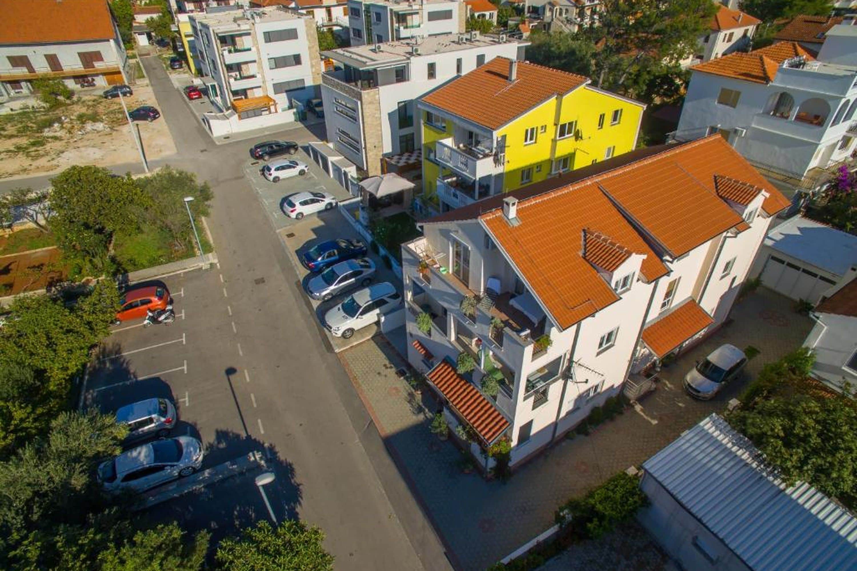 Luchtbeeld van een woongebied met meerdere gebouwen, een parkeerplaats en een straat.
