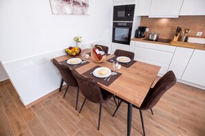 Un coin repas avec une table en bois dressée pour quatre personnes, entourée de chaises marron.