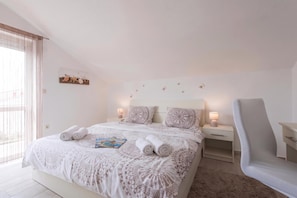 A hotel room with a large bed, two bedside tables, a chair, and a window with curtains. - Batur Pool Apartments (Zadar)