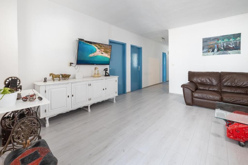 Ein Wohnzimmer mit einem weißen Schrank, einem braunen Ledersofa, einem Fernseher und einem Bild an der Wand.