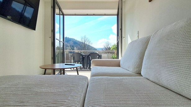 Ein Balkon mit einer Sitzecke, einem Tisch und Stühlen mit Blick auf eine schöne Aussicht.