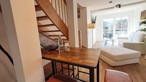 Eine moderne Küche mit einem Holztisch, Barhocker, einer Flasche und einem Glas auf der Arbeitsfläche.
