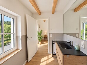 A modern kitchen with a black countertop, wooden beams, and a view of greenery outside. - Holiday apartment Bergblick in Winterberg for 4 guests (Winterberg)