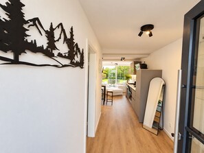 A hallway with a wooden floor leading to a kitchen area with a dining set and a view of a garden. - Holiday apartment Bergblick in Winterberg for 4 guests (Winterberg)