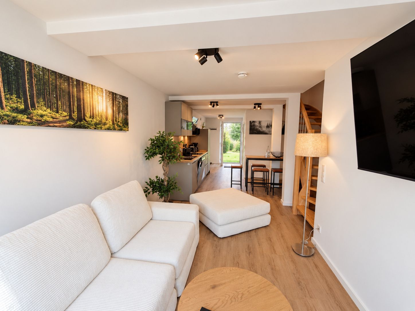 Ein modernes Wohnzimmer mit einer Couch, einem Couchtisch und einem Waldgemälde.