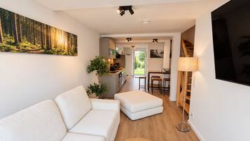 Un salon moderne avec un canapé, une table basse et un tableau représentant une forêt.