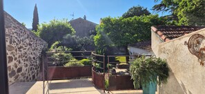A courtyard with a stone wall, metal railing, and potted plants. - Villa Dans le Golfe de Saint-tropez (Cogolin)