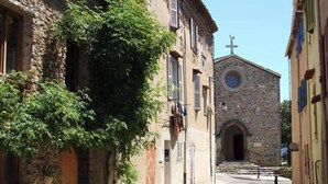 A narrow street with stone buildings, a church with a cross on top, and a tree with green leaves. - Villa Dans le Golfe de Saint-tropez (Cogolin)