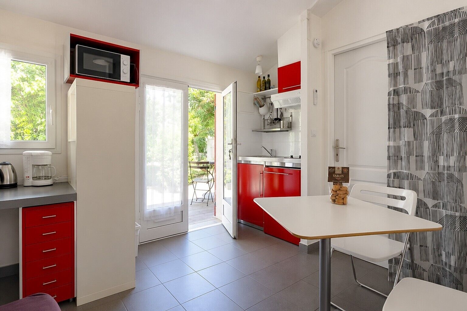 A compact kitchen with a microwave, coffee maker, and red cabinets.
